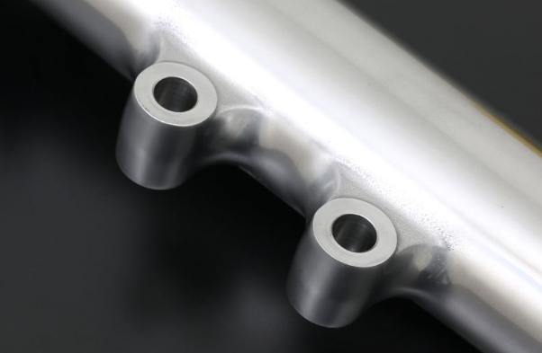 Close-up of a metallic pipe with circular openings on a dark background