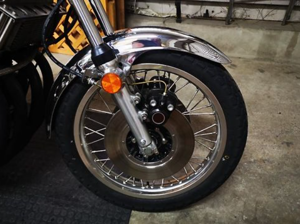 Close-up of a motorcycle wheel with a visible brand logo on a concrete floor.