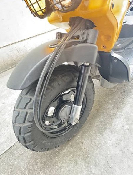 Close-up of a scooter wheel with a yellow background