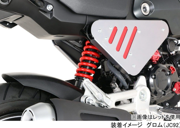Close-up of a motorcycle suspension system with red spring and black and gray metal components.