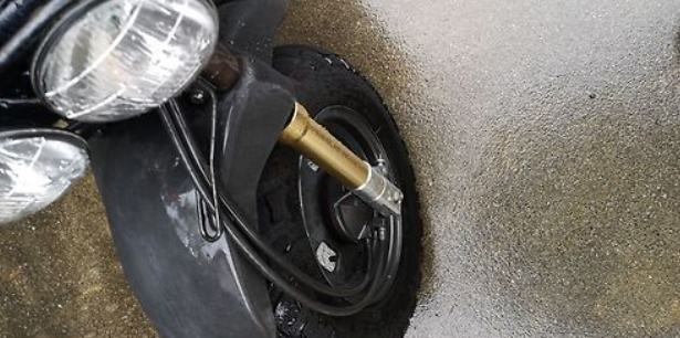 Close-up of a motorcycle's headlight and front wheel on a sandy surface
