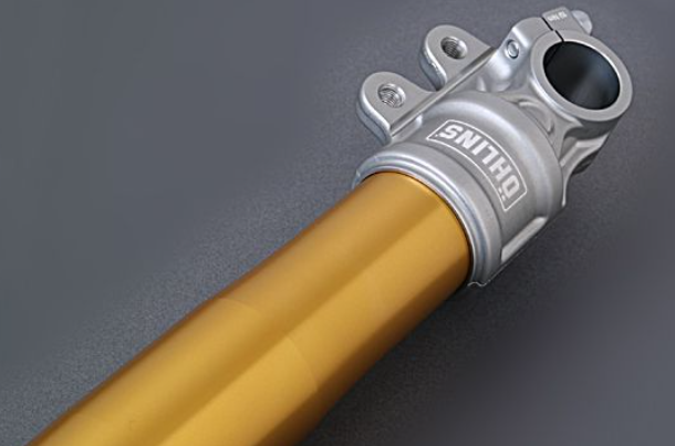 Close-up of a yellow suspension fork with a silver top cap on a gray background