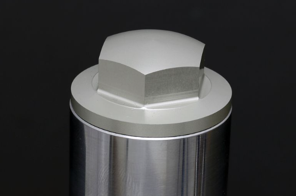 Metallic cylindrical object with a hexagonal cap on a black background