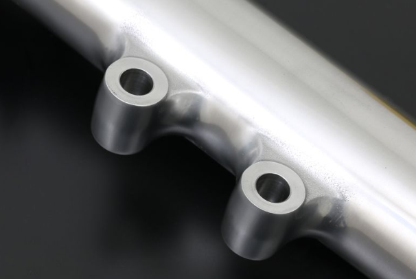 Close-up of a metallic exhaust pipe with two holes on a dark background