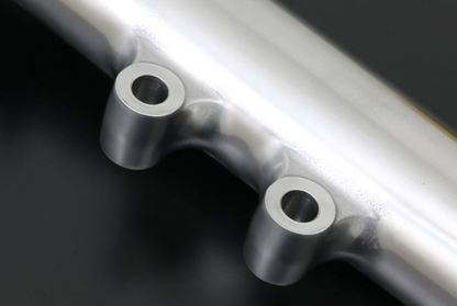 Close-up of a metallic exhaust pipe with two holes on a dark background