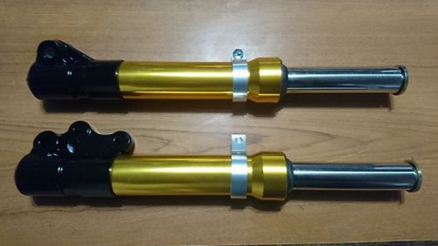 Two motorcycle shock absorbers on a wooden surface