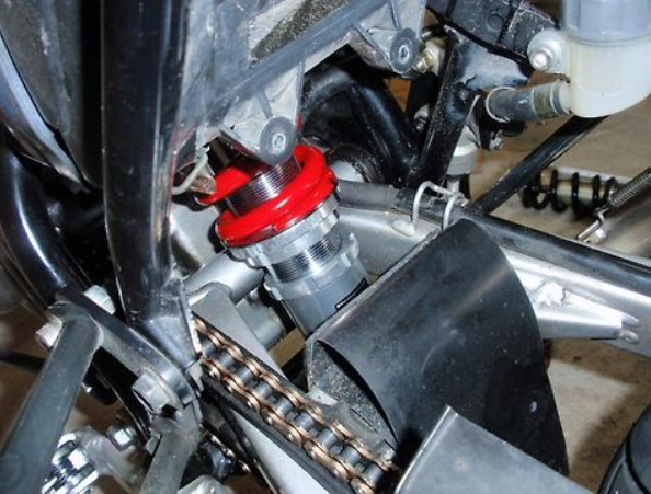 Close-up of a motorcycle chain and sprocket with a red component.