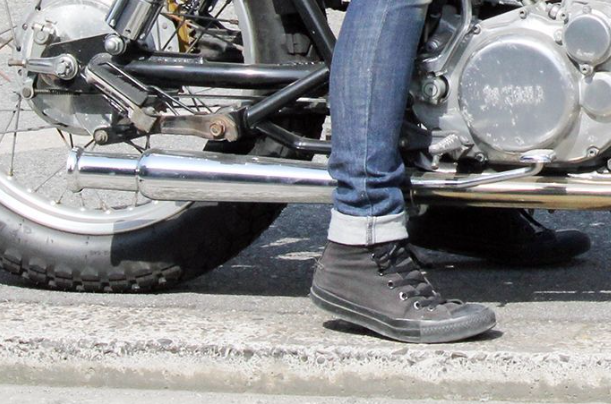 Person wearing black shoes and blue jeans sitting on a motorcycle.