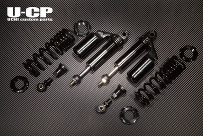 Set of black shock absorbers and springs on a carbon fiber background with U-CP branding.