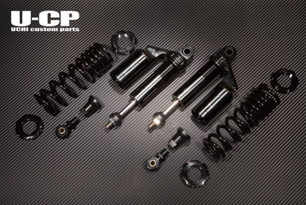 Set of black shock absorbers and springs on a carbon fiber background with U-CP branding.
