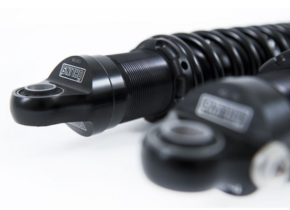 Close-up of a black motorcycle shock absorber on a white background