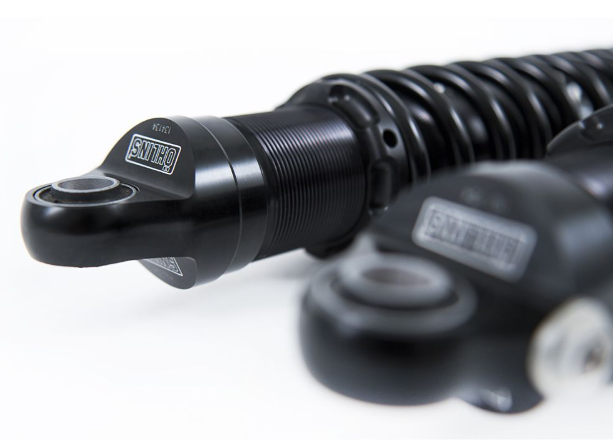 Close-up of a black motorcycle shock absorber on a white background