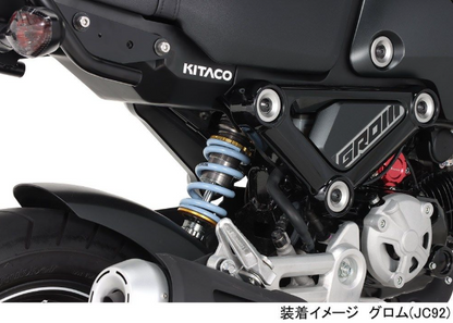 Close-up of a motorcycle suspension system with Kitaco branding on a white background