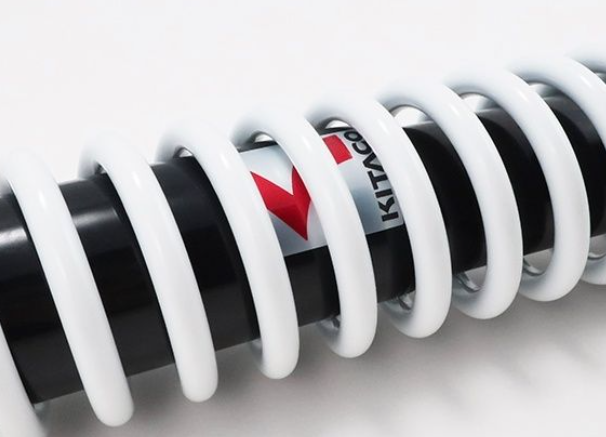 Close-up of a coil spring with Kit Carson logo on a white background
