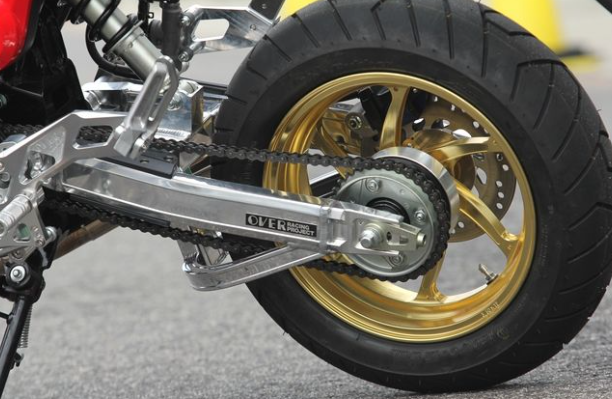 Close-up of a motorcycle chain and sprocket with a visible brand logo.
