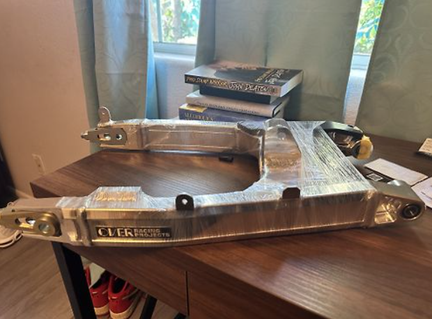 Metal bracket on a desk with books and a window in the background