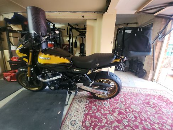 Yellow and black motorcycle inside a building with a pink rug on the floor.