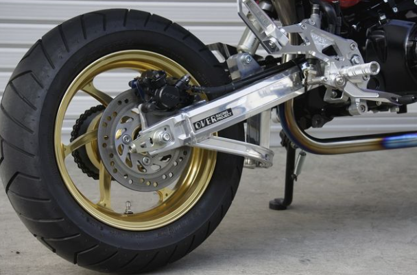 Close-up of a motorcycle wheel and suspension system on a concrete surface.
