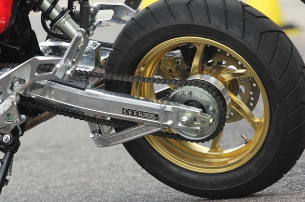 Close-up of a motorcycle chain and sprocket with a gold rim.