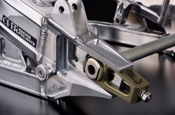 Close-up of a metallic mechanical component with 'Over Raging Projects' branding on a dark background.
