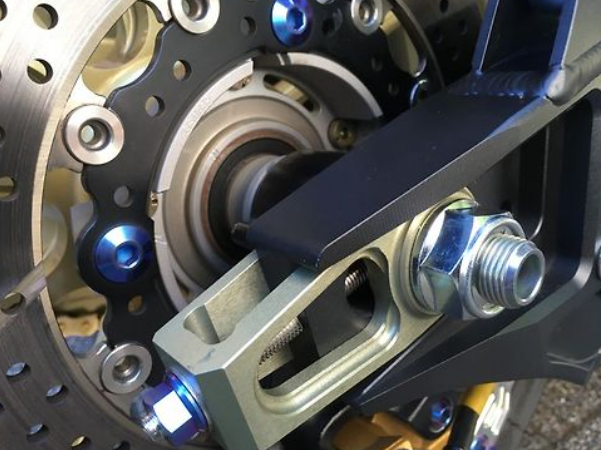 Close-up of a motorcycle chain and sprocket mechanism with metal components.