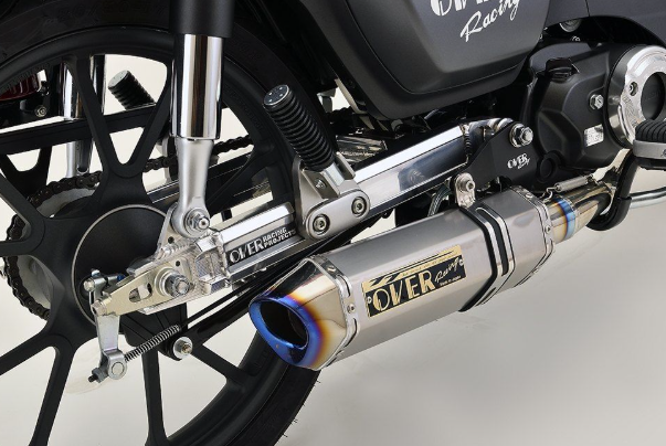 Close-up of a motorcycle exhaust with 'Over' branding on a gray background