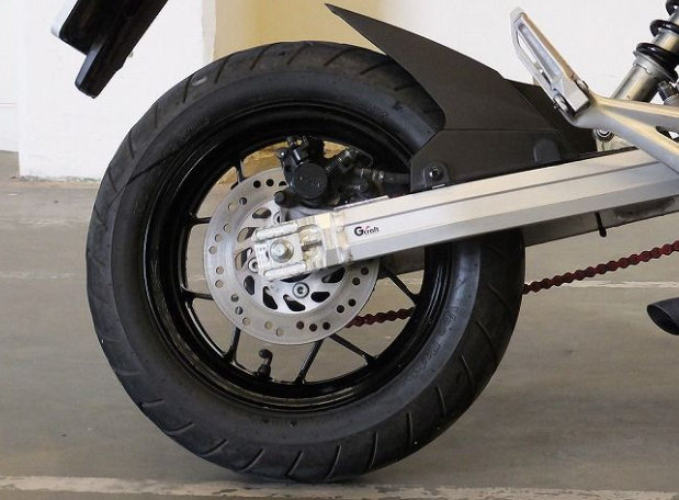 Close-up of a motorcycle wheel with disc brake on a concrete surface