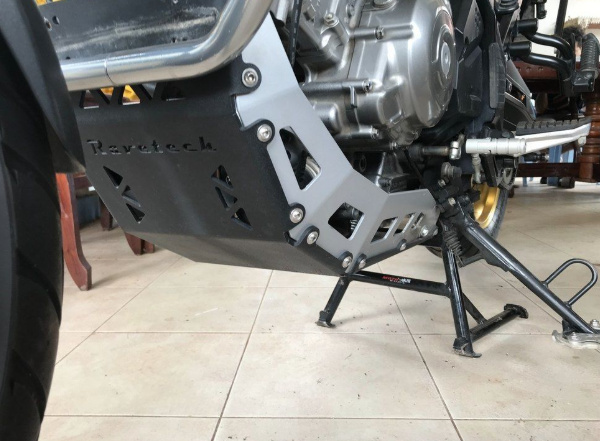 Close-up of a motorcycle engine and exhaust system on a tiled floor.