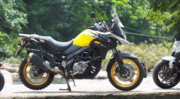 Motorcycle with yellow accents on a road with greenery in the background