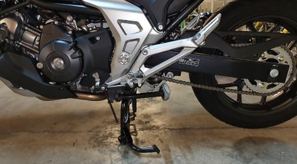 Close-up of a motorcycle's engine and exhaust system on a concrete floor.