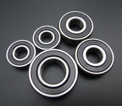 Five black bearings with silver inner races on a dark gray background
