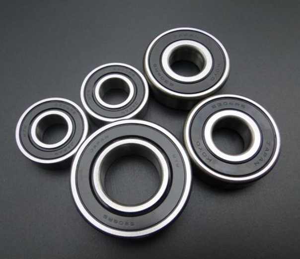Five black bearings with silver inner races on a dark gray background
