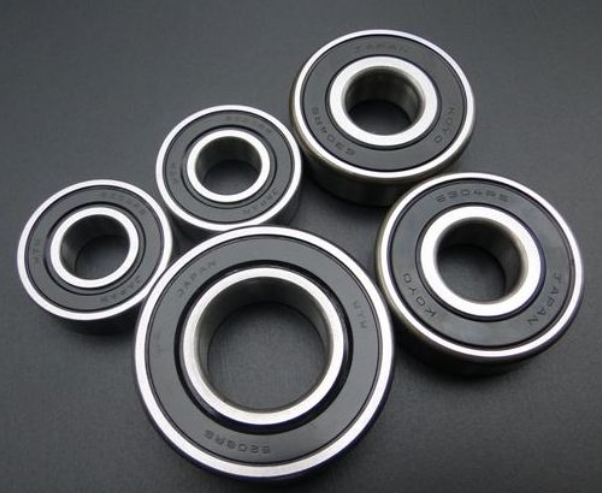 Five black bearings with silver inner races on a dark gray background