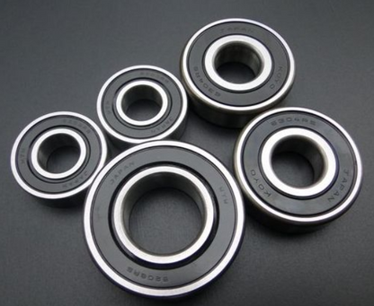Five black bearings with silver inner races on a dark gray background
