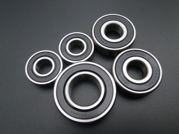 Five black bearings with metallic inner races on a dark gray background
