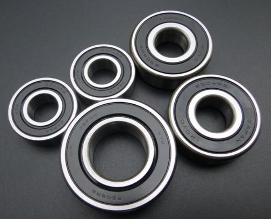 Five black bearings with silver inner races on a dark gray background