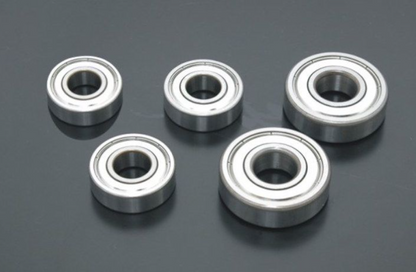 Five metal bearings on a dark reflective surface
