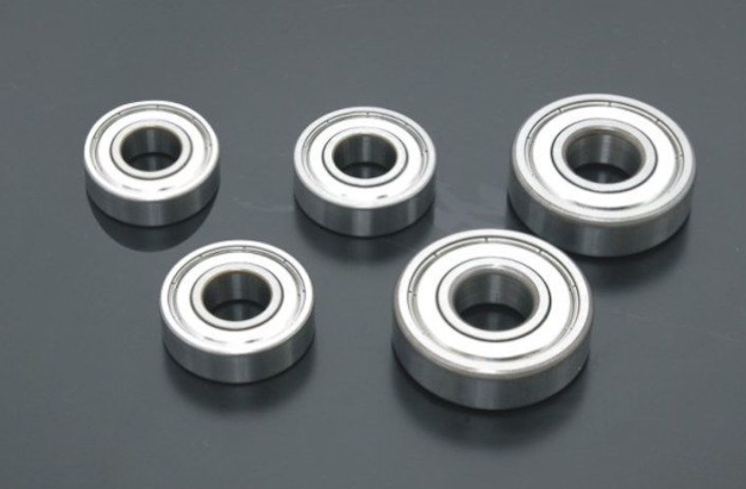 Five metal bearings on a dark reflective surface