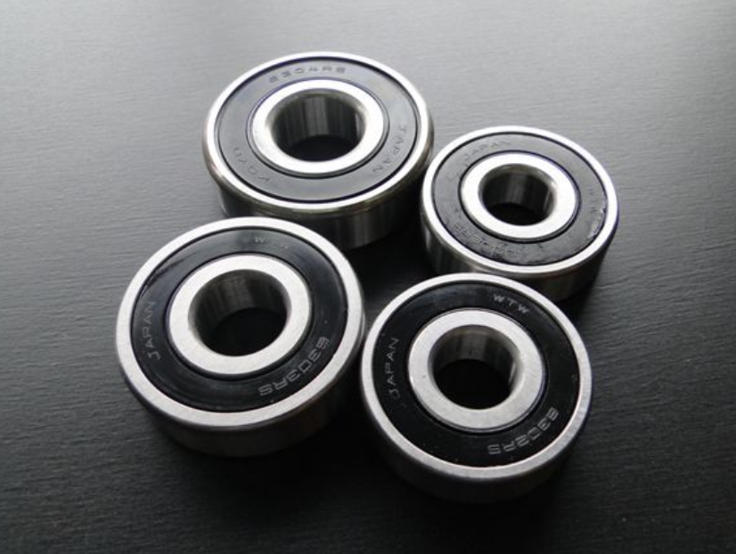 Four black bearings with metallic inner races on a dark surface