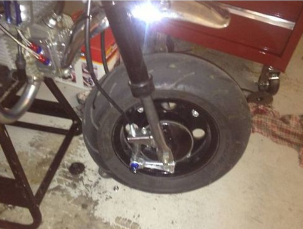 Close-up of a motorcycle tire and suspension system in a garage setting