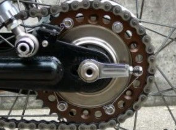 Close-up of a motorcycle chain and sprocket on a concrete surface