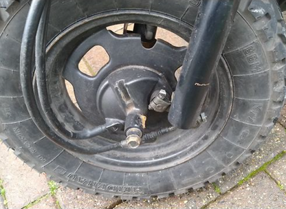 Close-up of a car tire with a visible hub and bolts on a concrete surface.