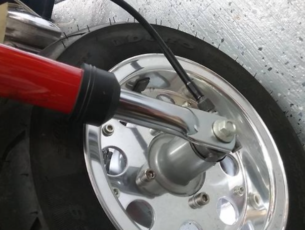 Close-up of a motorcycle wheel with a red tool on a textured background