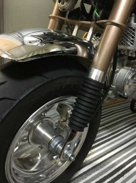 Close-up of a motorcycle wheel and fender on a striped floor.
