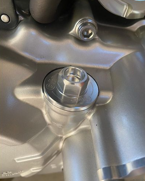 Close-up of a metallic bolt and engine component on a vehicle.