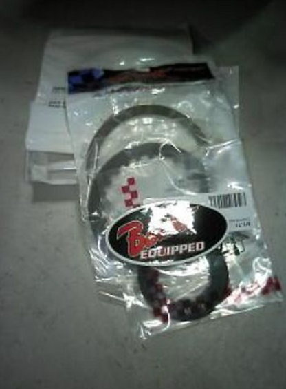 Two motorcycle exhaust gaskets in packaging with a brand logo on a gray surface.