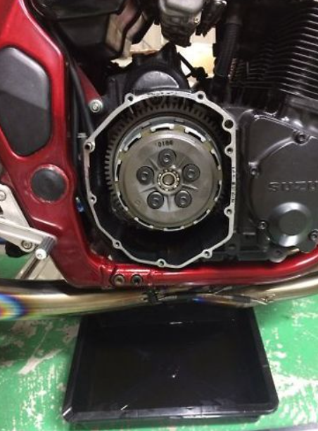 Motorcycle clutch mechanism on a red motorcycle with visible branding.