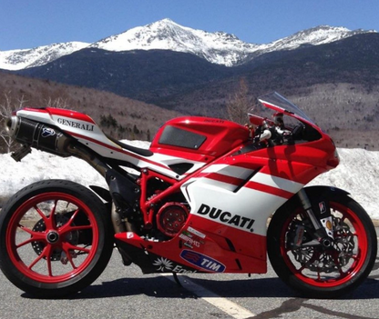 Red and white Ducati motorcycle on a road with mountains in the background