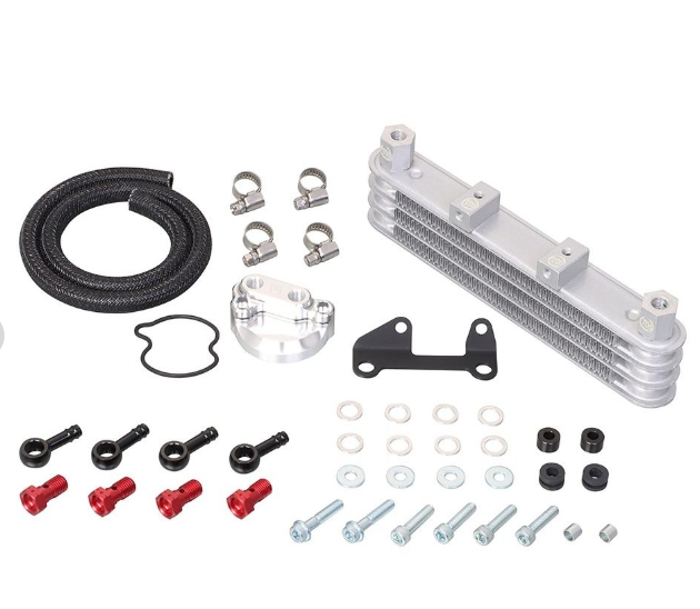 Collection of automotive parts including a metal oil cooler, hoses, and bolts on a white background