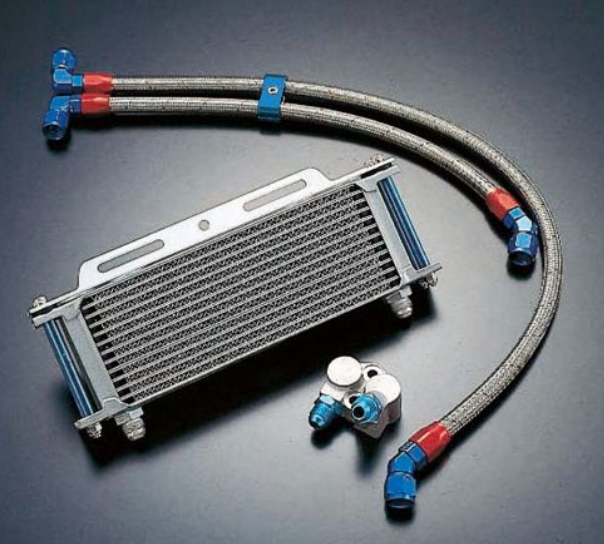 Metallic oil cooler with hoses and connectors on a dark background